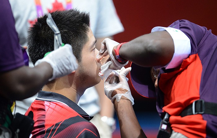 Andre Ho của Canda bị chấn thương ở mũi trong trận đấu vòng bảng môn bóng bàn.